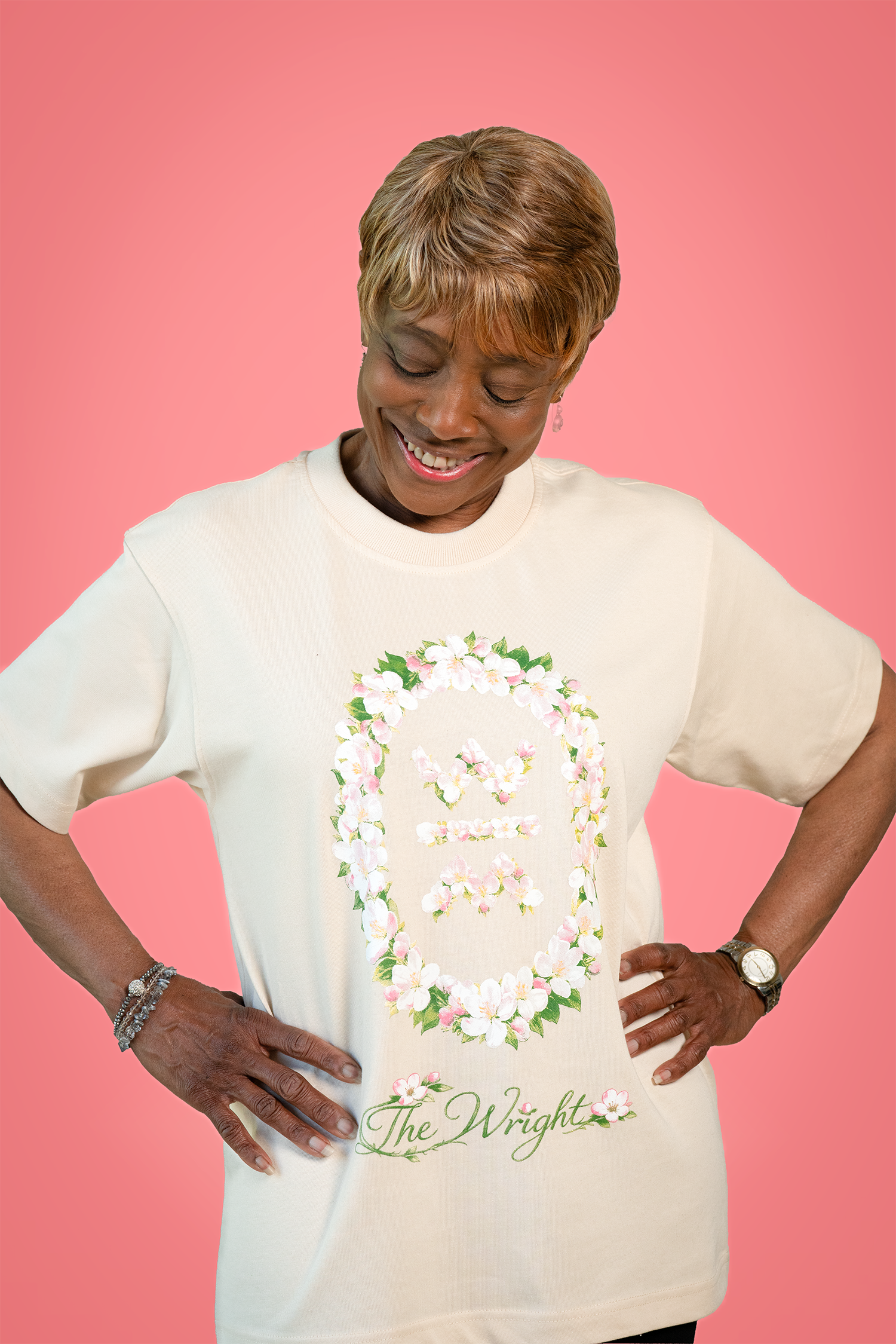 Woman wearing a white t-shirt with floral design and text on a pink background