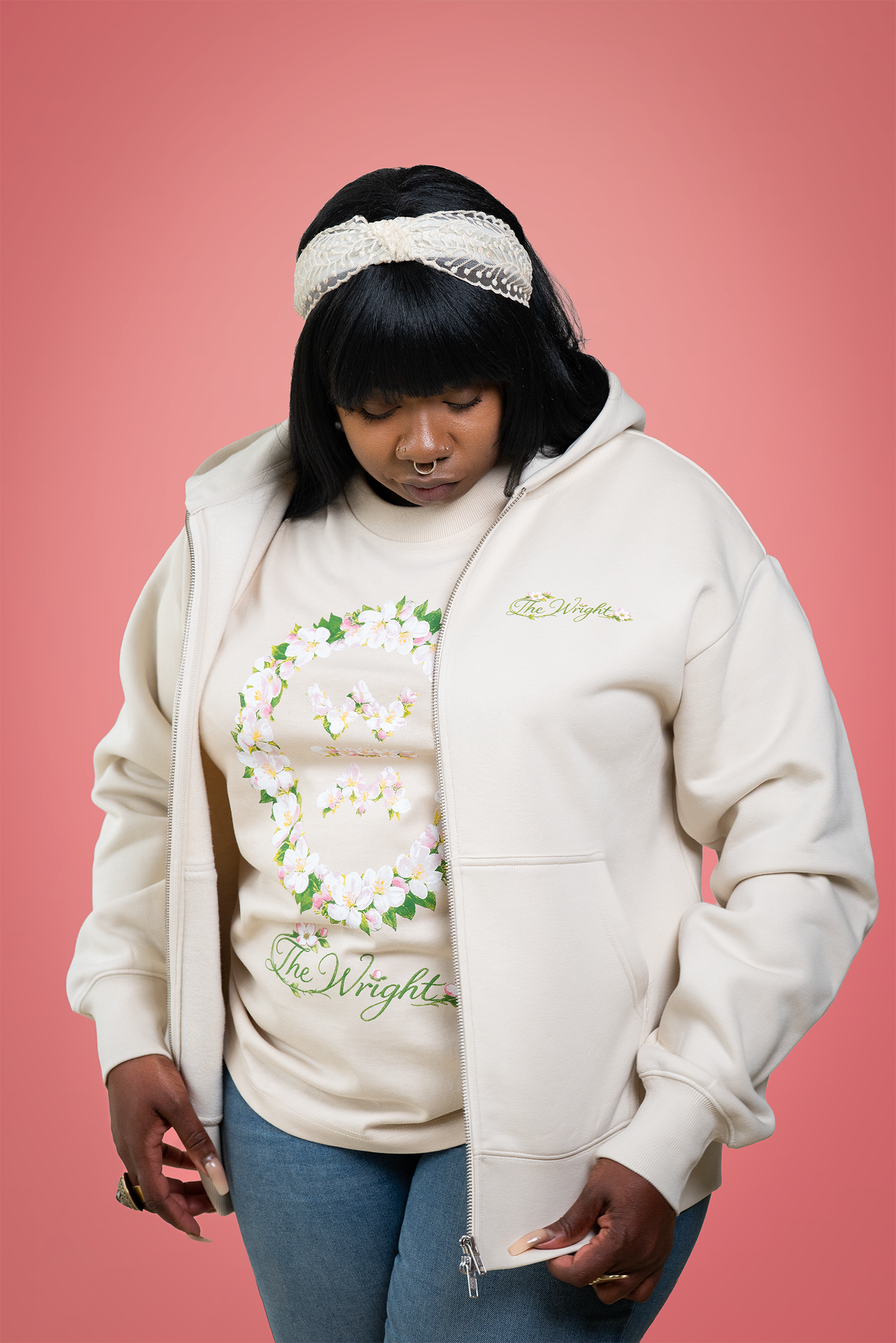 Person wearing a cream-colored hoodie with floral designs and text on a pink background